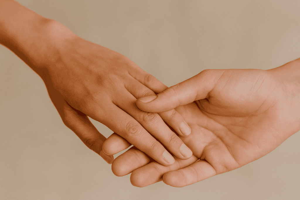 Two hands gently clasp each other against a neutral background, reflecting soothing touch for couples and an understanding of touch comfort.
